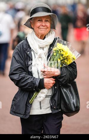 London, Großbritannien. 09. September 2022. Eine Frau hält einen Blumenstrauß, während sie die Mall entlang geht. Nach dem Tod von Königin Elizabeth II. Legen viele Trauernde, aber auch viele Touristen Blumen nieder und zollen ihren Tribut an den Toren des Buckingham Palace, und die Gegend wird sehr voll mit Menschen. Kredit: Imageplotter/Alamy Live Nachrichten Stockfoto