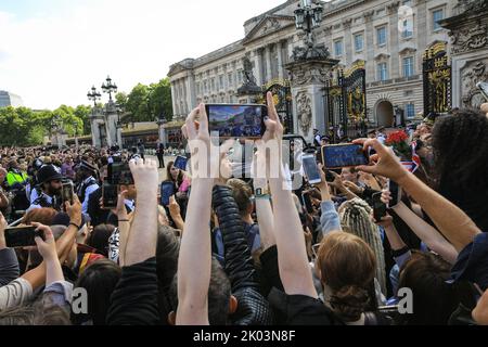 London, Großbritannien. 09. September 2022. Die Leute halten ihre Handys hoch, um einen Blick auf König Charles zu werfen, der zu den Ehrungen geht. Nach dem Tod von Königin Elizabeth II. Legen viele Trauernde, aber auch viele Touristen Blumen nieder und zollen ihren Tribut an den Toren des Buckingham Palace, und die Gegend wird sehr voll mit Menschen. Kredit: Imageplotter/Alamy Live Nachrichten Stockfoto