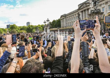 London, Großbritannien. 09. September 2022. Die Leute halten ihre Handys hoch, um einen Blick auf König Charles zu werfen, der zu den Ehrungen geht. Nach dem Tod von Königin Elizabeth II. Legen viele Trauernde, aber auch viele Touristen Blumen nieder und zollen ihren Tribut an den Toren des Buckingham Palace, und die Gegend wird sehr voll mit Menschen. Kredit: Imageplotter/Alamy Live Nachrichten Stockfoto