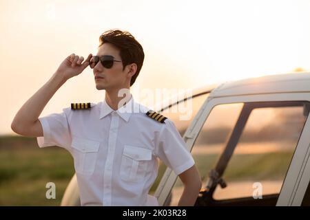 Chinesischer Hubschrauberpilot, der neben dem Fahrzeug steht Stockfoto