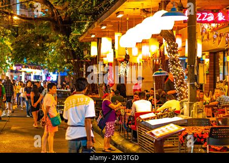 BANGKOK, THAILAND - 1.11.2019: Straßenmarkt mit Street Food, Pubs und Geschäften in Bangkok. Blick in die Nacht auf die Menschen, die auf der Straße spazieren gehen und einkaufen gehen Stockfoto