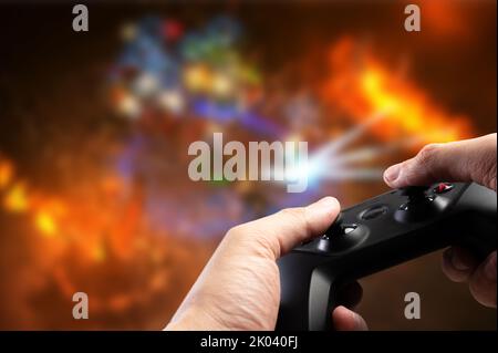 Joystick, Gamepad GAM22ICB in den Händen einer Person auf einem hellen Fantasy-Hintergrund. Videospiele, Unterhaltung, Wettbewerbe, Kommunikation mit Freunden Stockfoto