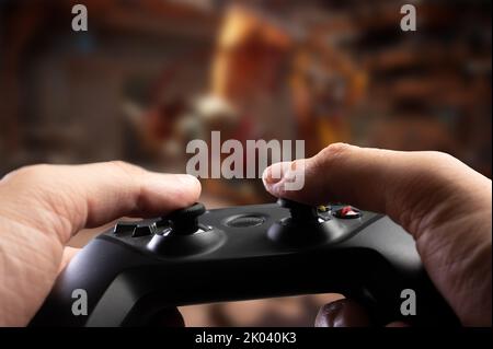 Gamepad, Joystick GAM22ICB in den Händen eines Mannes auf einem Fantasy-Hintergrund. Nahaufnahme. Videospiele, Virtual Reality. Jugendkultur. Kommunikation, compe Stockfoto