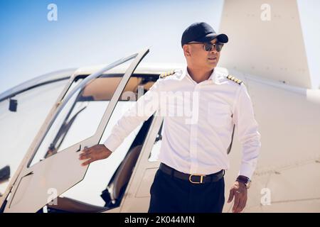 Chinesischer Hubschrauberpilot, der neben dem Fahrzeug steht Stockfoto