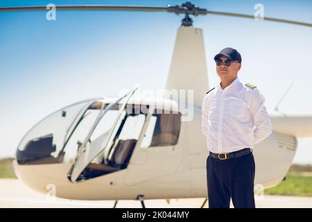 Chinesischer Hubschrauberpilot, der neben dem Fahrzeug steht Stockfoto