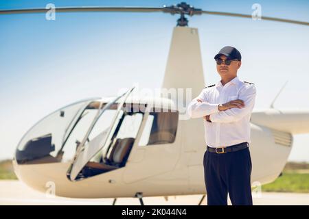 Chinesischer Hubschrauberpilot, der neben dem Fahrzeug steht Stockfoto
