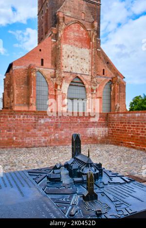 Gegossenes Miniaturmodell der Sankt Marienkirche mit dem Turm des Originals im Hintergrund, Wismar, Deutschland. Stockfoto