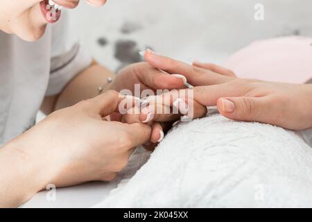 Sehr glücklich latina Frau Maniküre Spezialist, Peeling von den falschen Nägeln nach der Anwendung der Polygel Flüssigkeit Gel richtig. Konzept der Schönheit und Stockfoto