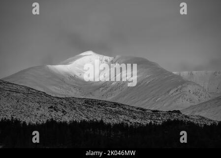 Schwarz-Weiß-Alpen Glow trifft Berggipfel in den schottischen Highlands während eines atemberaubenden Sonnenaufgangs in der Winterlandschaft Stockfoto