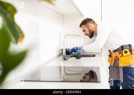 Klempner installiert Küchenarmatur. Sanierung in der Wohnung. Stockfoto