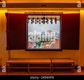 Blick vom Fenster in den Wak Saket Tempel (Goldener Berg) in Bangkok City, Thailand. Altes Holzfenster mit historischem Rahmen und Herzglocken. In Far Stockfoto
