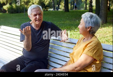 Ältere Paar multirassische Ehegatten sitzen Ruhe auf Bank genießen Gespräch im öffentlichen Sommerpark mit freundlichen Gespräch teilen Gedanken oder Nachrichten während Meetin Stockfoto
