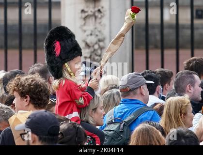 © Jeff Moore Ein junges Mädchen, das als Wache gekleidet ist, sitzt auf den Schultern ihrer Mutter, während sie der verstorbenen Königin Elizabeth II. Vor Buckingham P ihren Respekt zollt Stockfoto