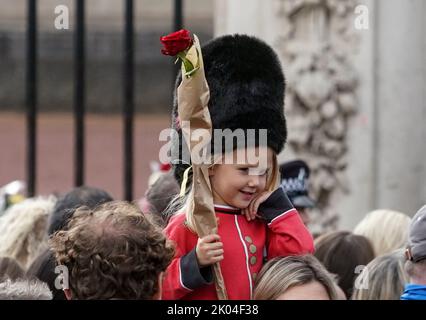 © Jeff Moore Ein junges Mädchen, das als Wache gekleidet ist, sitzt auf den Schultern ihrer Mutter, während sie der verstorbenen Königin Elizabeth II. Vor Buckingham P ihren Respekt zollt Stockfoto