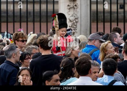 © Jeff Moore Ein junges Mädchen, das als Wache gekleidet ist, sitzt auf den Schultern ihrer Mutter, während sie der verstorbenen Königin Elizabeth II. Vor Buckingham P ihren Respekt zollt Stockfoto