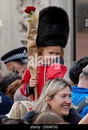 © Jeff Moore Ein junges Mädchen, das als Wache gekleidet ist, sitzt auf den Schultern ihrer Mutter, während sie der verstorbenen Königin Elizabeth II. Vor Buckingham P ihren Respekt zollt Stockfoto