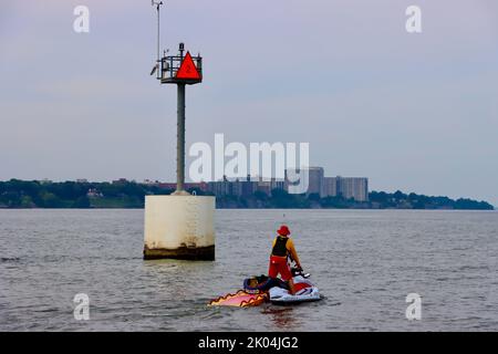 Mann auf dem Jetski am Eingang zum Hafen von Cleveland mit Gebäuden der Gold Coast im Hintergrund. Stockfoto