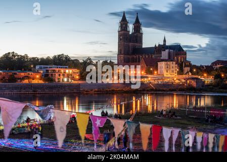 Magdeburg, Deutschland. 09. September 2022. Auf den Elbwiesen tanzen junge Menschen vor einer historischen Kulisse, dem Magdeburger Dom. Am Abend begann in der Landeshauptstadt das dreitägige Festival der Kulturbrücke. Das Programm umfasst Konzerte, Theateraufführungen, Lesungen und Tanzworkshops. Quelle: Stephan Schulz/dpa/Alamy Live News Stockfoto