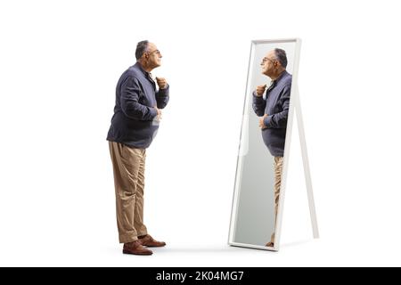 In voller Länge Profilaufnahme eines reifen Mannes, der sich bereit gemacht hat und einen auf weißem Hintergrund isolierten Spiegel ansieht Stockfoto