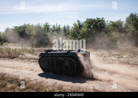 Evakuierungsroboter Them wird während der Feldtests auf einer staubigen Straße gesehen. Feldtests der Multizweck-Crawler-Drohne Themis der estnischen Firma Milrem Robotics, die vom medizinischen Bataillon „Hospitalers“ für Evakuierungszwecke an der Front verwundete Soldaten eingesetzt werden soll. Der Evakuierungsroboter „Zhuravel“ bestand den ersten Test. Der Roboter wird an vorderster Front eingesetzt, an Orten, an denen es für Mediziner schwierig ist, mit dem Fahrzeug oder zu Fuß zu erreichen. Stockfoto