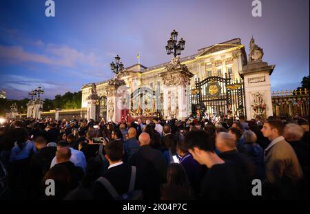 London, Großbritannien. 09. September 2022. Hunderte von Menschen gehen langsam am Haupteingang des Buckingham Palace vorbei, der mit Blumen und Trauerbotschaften geschmückt ist. Die britische Königin Elizabeth II. Starb am 08.09.2022 im Alter von 96 Jahren. Quelle: Christian Charisius/dpa/Alamy Live News Stockfoto