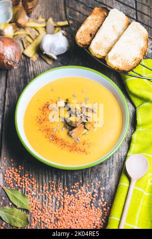 Vegane Suppe aus roten Linsen, Kartoffeln, Knoblauch, Zwiebeln, Lorbeerblatt, Creme auf pflanzlicher Basis. Gerösteter Tofu und Brotscheiben. Suppe voller pflanzlicher Proteine. Stockfoto