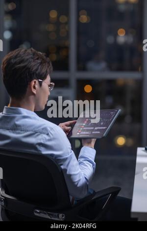 Chinesischer Geschäftsmann, der nachts im Büro arbeitet Stockfoto