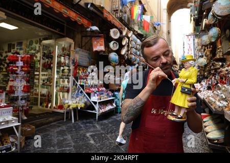 Der Handwerker Gennaro Di Virgilio arbeitet in seinem Laden in der Via San Gregorio Armeno, der berühmten Straße in Neapel, die der Herstellung von Krippenfiguren gewidmet ist, an einer Figur, die Königin Elisabeth II. Darstellt Stockfoto