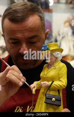 Der Handwerker Gennaro Di Virgilio arbeitet in seinem Laden in der Via San Gregorio Armeno, der berühmten Straße in Neapel, die der Herstellung von Krippenfiguren gewidmet ist, an einer Figur, die Königin Elisabeth II. Darstellt Stockfoto