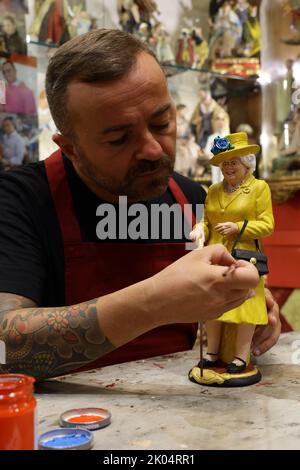 Der Handwerker Gennaro Di Virgilio arbeitet in seinem Laden in der Via San Gregorio Armeno, der berühmten Straße in Neapel, die der Herstellung von Krippenfiguren gewidmet ist, an einer Figur, die Königin Elisabeth II. Darstellt Stockfoto