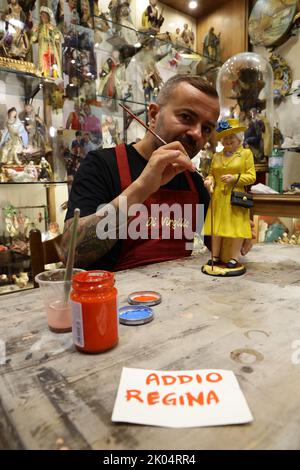 Der Handwerker Gennaro Di Virgilio arbeitet in seinem Laden in der Via San Gregorio Armeno, der berühmten Straße in Neapel, die der Herstellung von Krippenfiguren gewidmet ist, an einer Figur, die Königin Elisabeth II. Darstellt Stockfoto