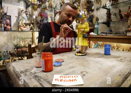 Der Handwerker Gennaro Di Virgilio arbeitet in seinem Laden in der Via San Gregorio Armeno, der berühmten Straße in Neapel, die der Herstellung von Krippenfiguren gewidmet ist, an einer Figur, die Königin Elisabeth II. Darstellt Stockfoto