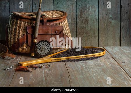 Vintage Fliegenfischerrute Kreel und Netz auf altem Holz Hintergrund Stockfoto