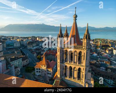 Eine Drohnenaufnahme der Kathedrale von Lausanne, der Stadt und des Genfer Sees bei Sonnenaufgang im August Stockfoto