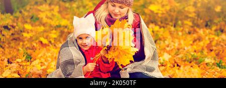 Mutter- und Kinderhände im Herbstpark inmitten der orange gefallenen Blätter Stockfoto