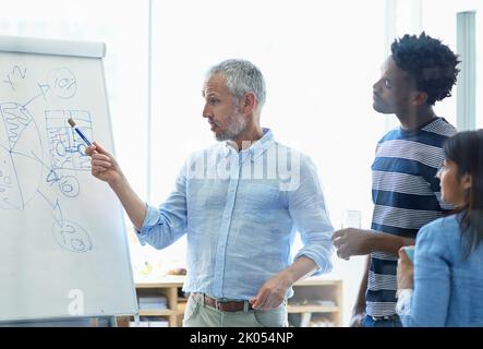 Ein reifer Geschäftsmann trifft sich mit seinem kreativen Team. Stockfoto