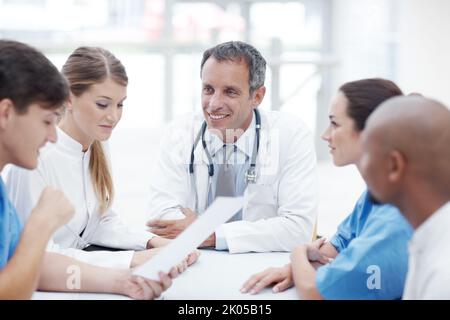 Treffen von medizinischen Köpfen. Eine Gruppe von medizinischen Fachkräften, die an einem Sitzungstisch sitzen und eine Diskussion führen. Stockfoto