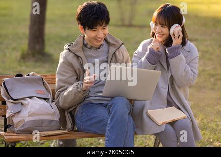 Glückliche chinesische College-Studenten mit Laptop auf dem Campus Stockfoto