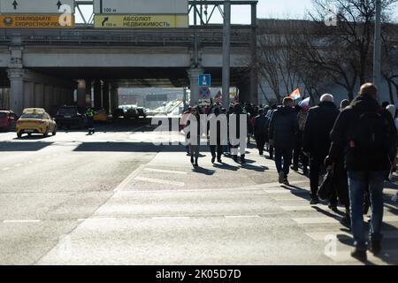 Viele Leute laufen durch die Stadt. Menschen während der Hauptverkehrszeit. Über die Autobahn. Fußgängerüberweg in der Stadt. Stockfoto