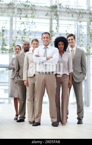 Unaufhaltsame Geschäftskraft. Die gesamte Länge eines dynamischen Geschäftsteams, das selbstbewusst mit seinem Teamleiter – Copyspace – zusammensteht. Stockfoto