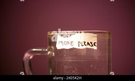 Leeres Trinkglas Kaffee mit Textwort mehr bitte auf Klebeband geschrieben Stockfoto