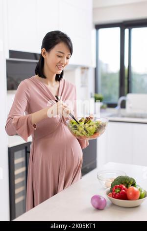 Glücklich Chinesisch schwanger Frau Kochen in der Küche Stockfoto