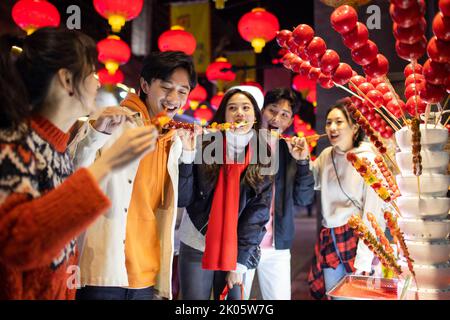 Junge chinesische Freunde mit kandierter Haw feiern das chinesische Neujahr Stockfoto