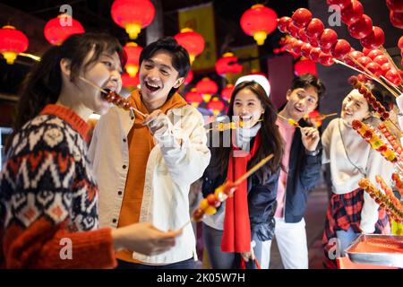 Junge chinesische Freunde mit kandierter Haw feiern das chinesische Neujahr Stockfoto