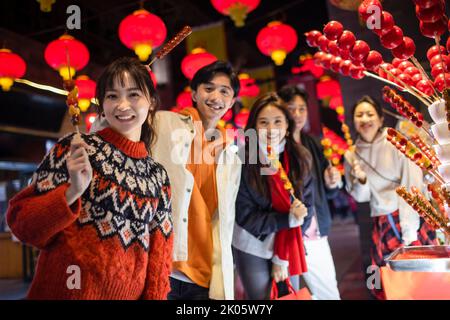 Junge chinesische Freunde mit kandierter Haw feiern das chinesische Neujahr Stockfoto