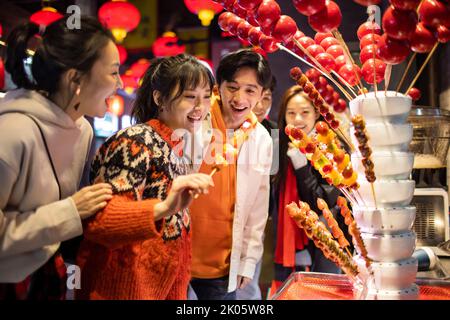 Junge chinesische Freunde mit kandierter Haw feiern das chinesische Neujahr Stockfoto