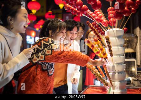 Junge chinesische Freunde mit kandierter Haw feiern das chinesische Neujahr Stockfoto