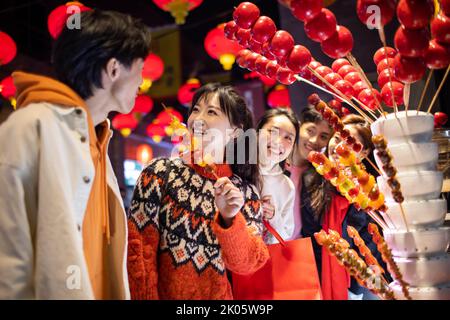 Junge chinesische Freunde mit kandierter Haw feiern das chinesische Neujahr Stockfoto