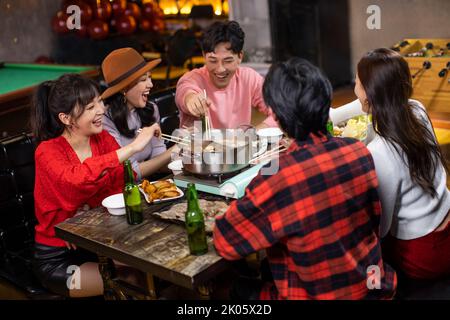 Junge chinesische Freunde, die im Hotpot-Restaurant zu Abend essen Stockfoto