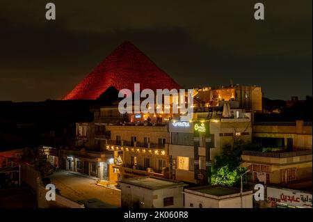 Kairo/Ägypten. 08/28/2022.Blick auf eine Straße in Kairo und die beleuchteten Pyramiden von Cheops und Khepre im Hintergrund Stockfoto